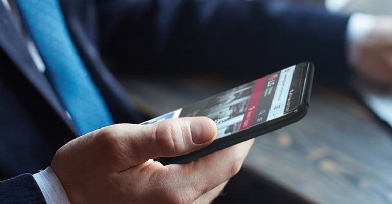 Zdjęcie mężczyzny trzymającego smartfon, na którego ekranie jest wyświetlona strona internetowa LG.